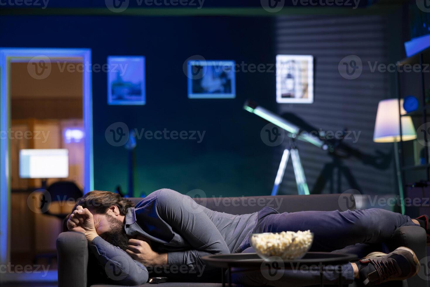 Sad man lounged on couch crying after finishing heartbreaking drama movie on streaming service. Upset person laying down and weeping after TV show favorite character dies photo