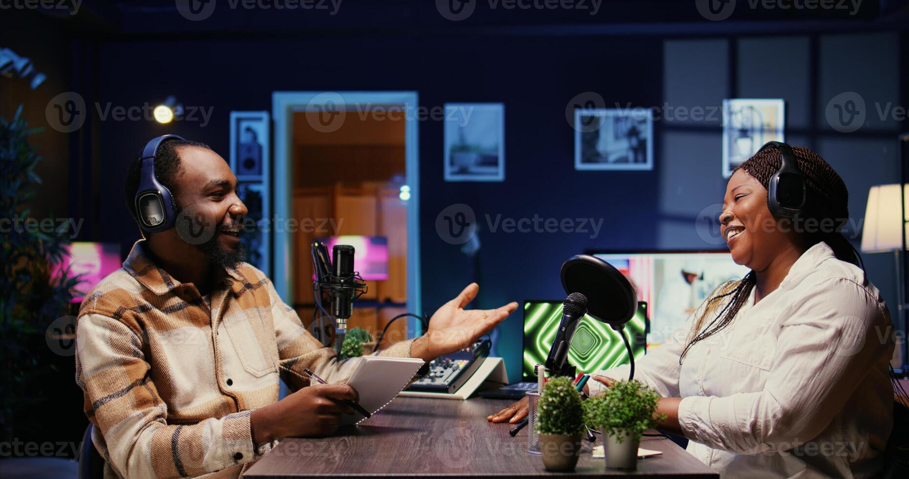 African american influencer starting podcast session with woman, talking in studio. Happy presenter bumping fists with guest, ready to begin recording for live internet show photo