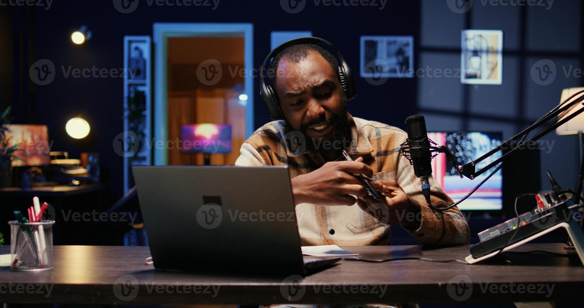 Portrait of african american tech expert reviewing newly released smartphone in rgb lights living room studio. Entertaining influencer filming technology channel vlog using professional camera photo