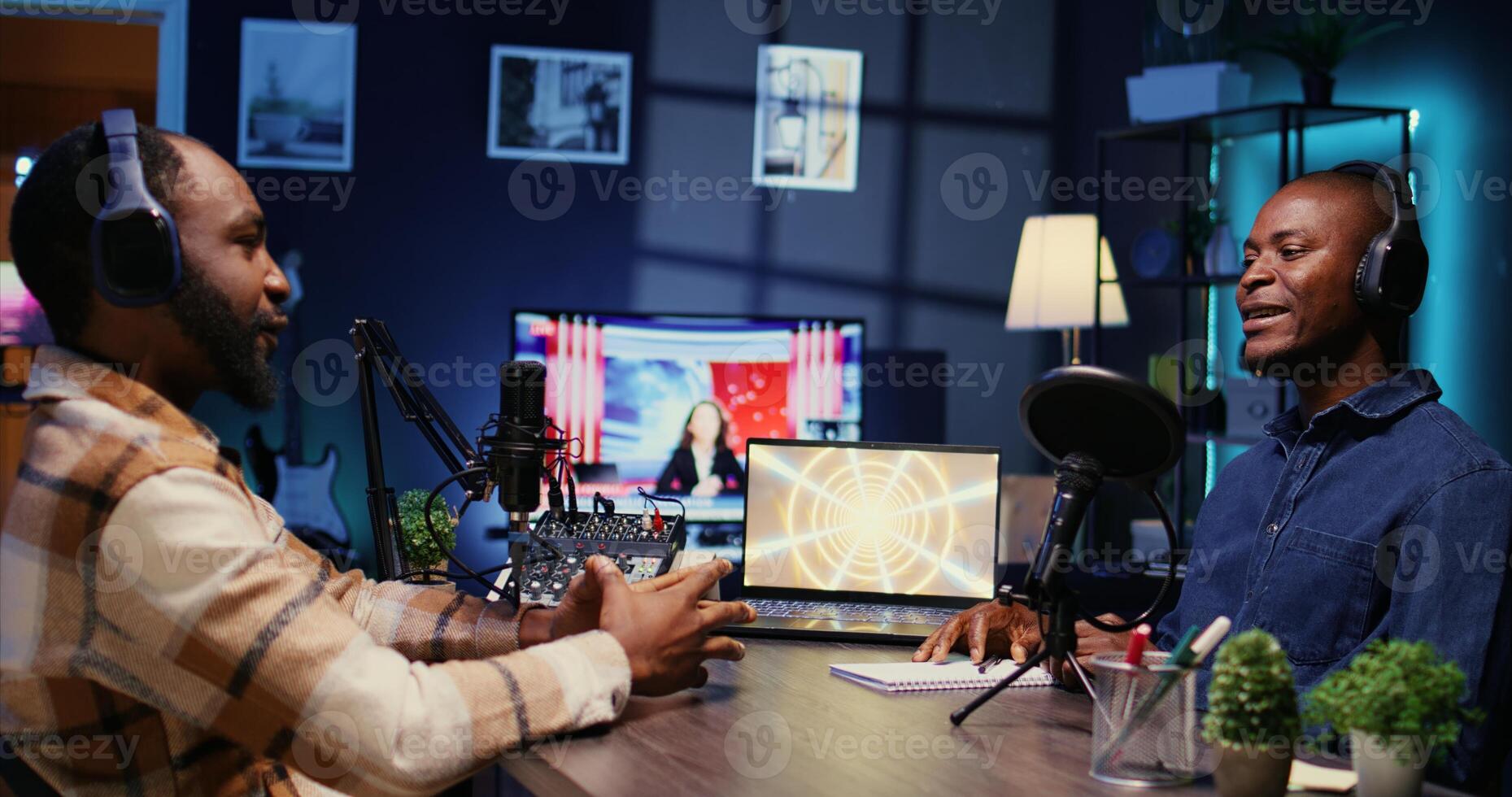 African american influencer recording podcast with guest, using audio recording equipment in home studio. Cheerful men chatting live during broadcasting session for internet show photo