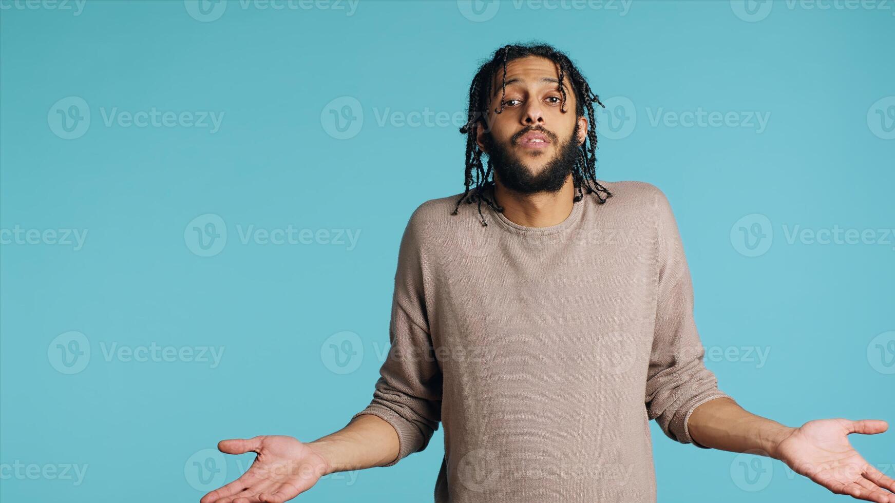 Uncaring Middle Eastern man shrugging shoulders, showing indifference and apathy. Careless BIPOC person doing nonchalant indifferent hand gesturing, isolated over studio background, camera A photo