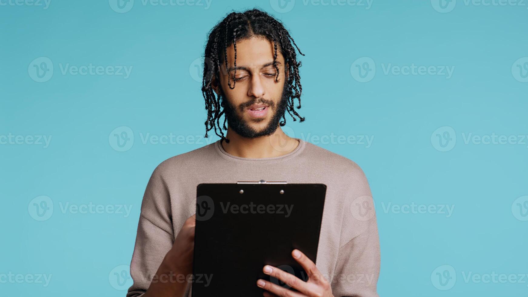 Public speaker reading from clipboard files, preparing discourse, rehearsing before doing speech. Middle Eastern orator telling monologue, isolated over studio background, camera B photo
