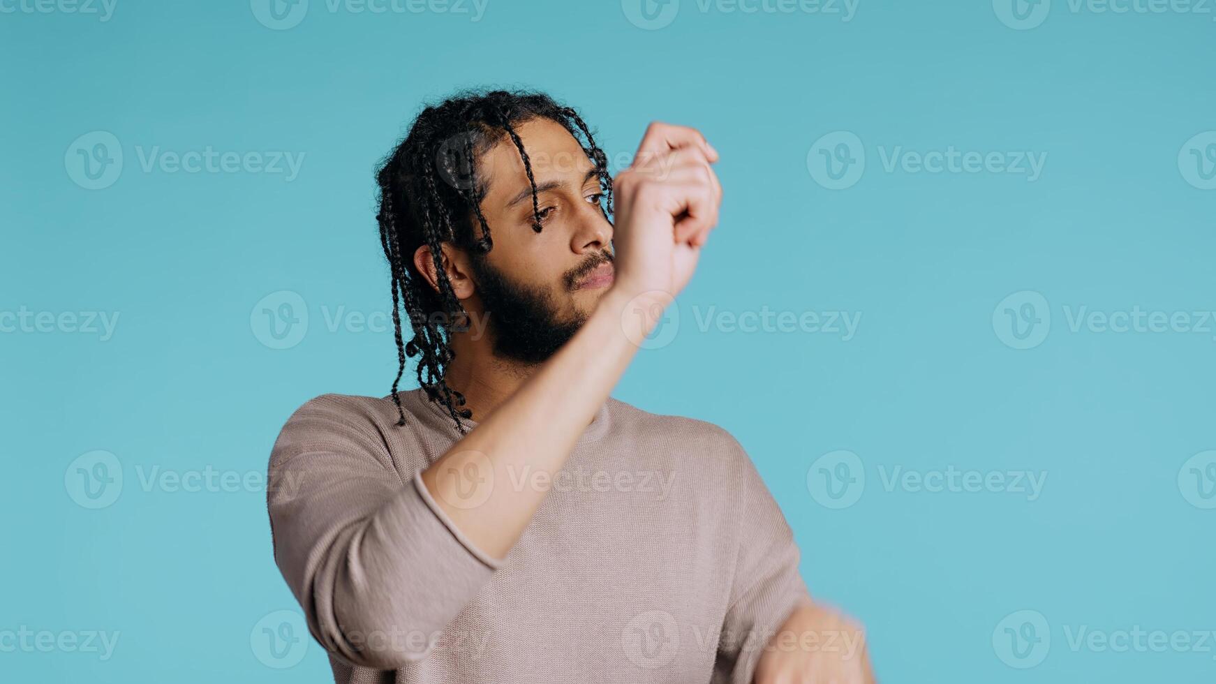 Middle Eastern conductor performing classical music concert following imaginary sheet music. Man doing delicate swinging hand motions, pretending to conduct orchestra, studio background, camera B photo