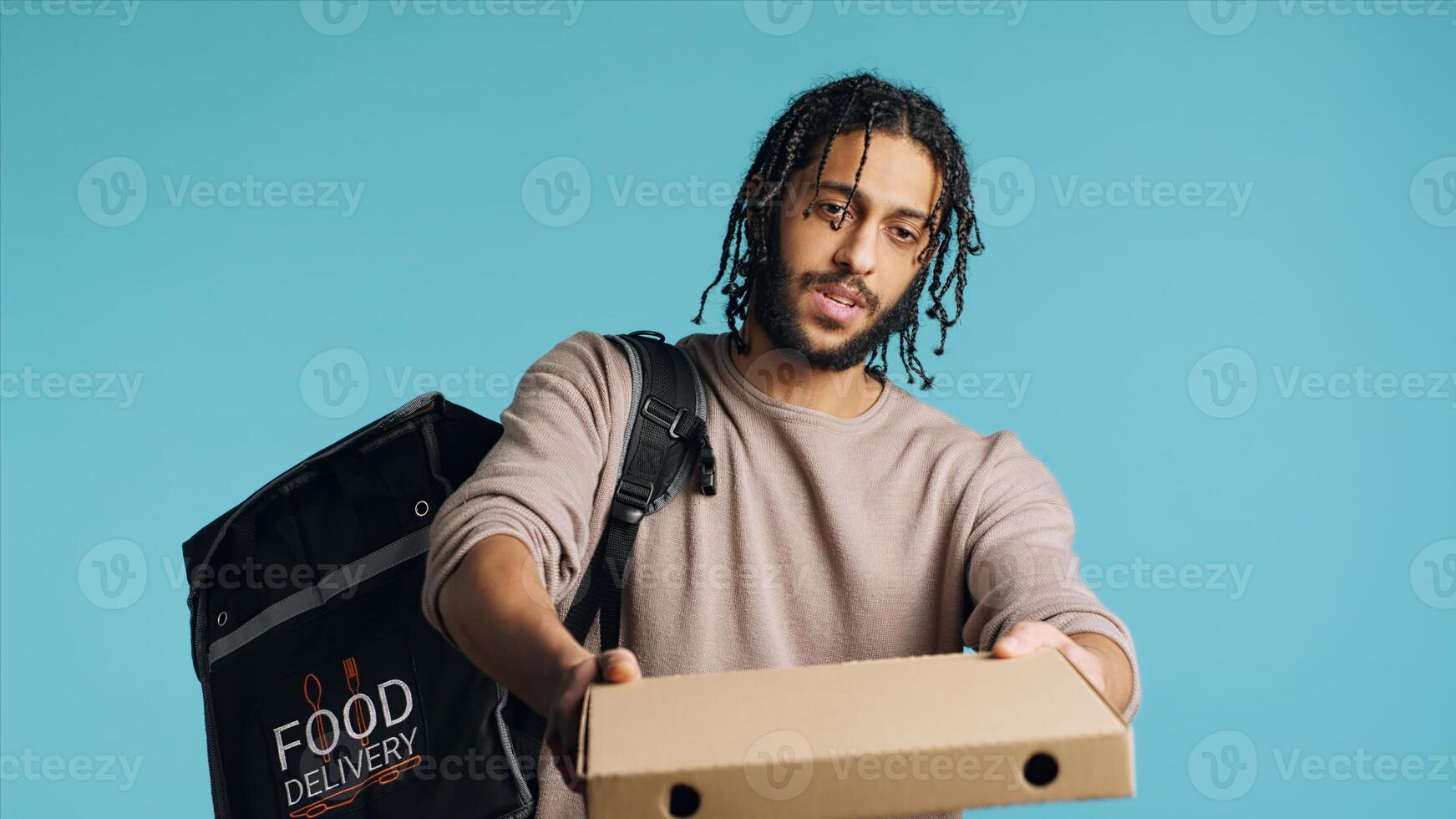Portrait of BIPOC courier delivering pizza order to client. Delivery part time worker using thermal backpack to store food and bring it to customer, isolated over studio background, camera A photo