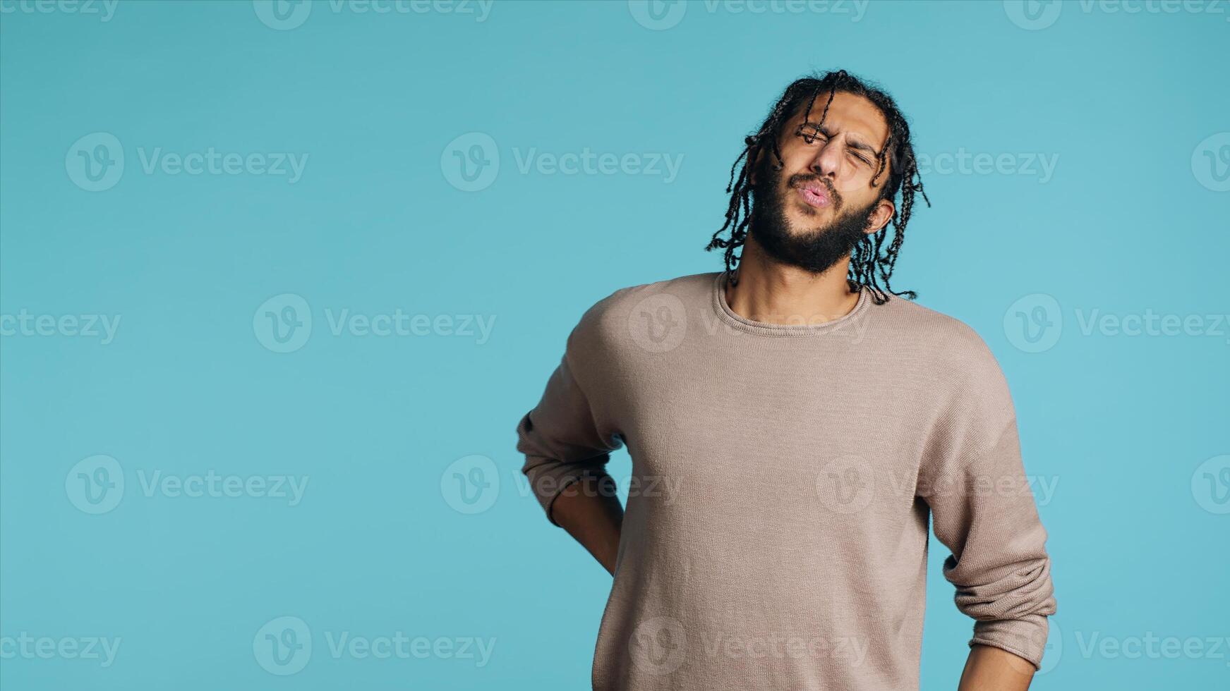Hurt Middle Eastern man screaming from pain, suffering from back injury, having health problems. Injured BIPOC person feeling uncomfortable ache, yelling, studio background, camera A photo