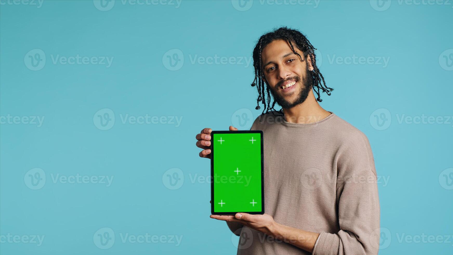 Joyful man holding green screen tablet, showing positive emotion. Upbeat person presenting chroma key device, doing recommendation, isolated over studio background, camera A photo