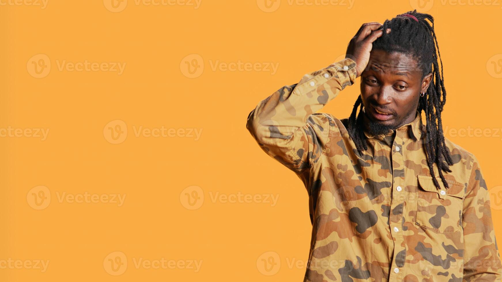Pensive african american guy is confused and sceptic, contemplating about something in studio. Young man being uncertain and clueless about answer, reflective focused adult. Handheld shot. photo