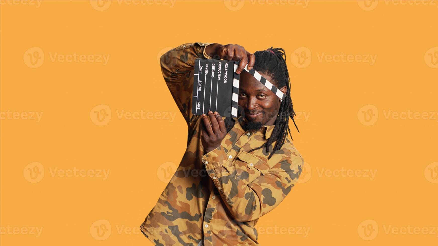 Male model posing with clapperboard in front of camera, using movie production instrument to cut scenes and say action. African american film director and producer holding flap board. photo