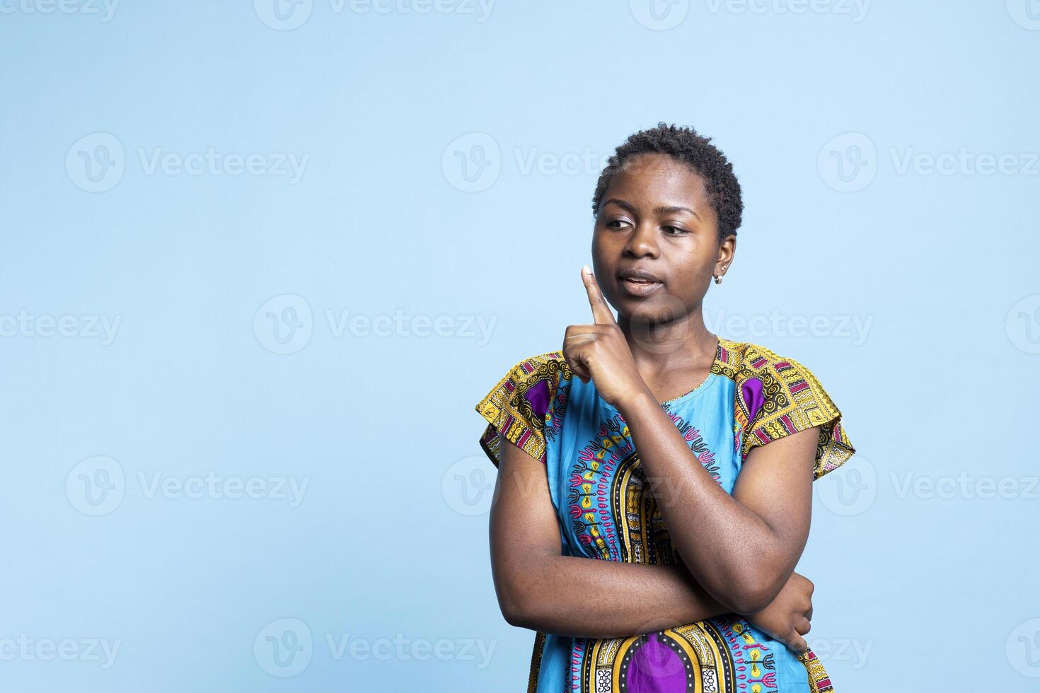 African american gorgeous person trying to find new solutions, being uncertain and contemplating about innovative ideas. Young female model feels unsure, wearing colorful ethnic costume. photo