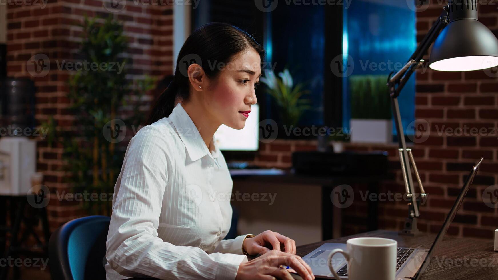 Businesswoman transcribing information from laptop to notepad, doing tasks for team project in office overnight. Worker working late at night, writing down data from computer screen photo