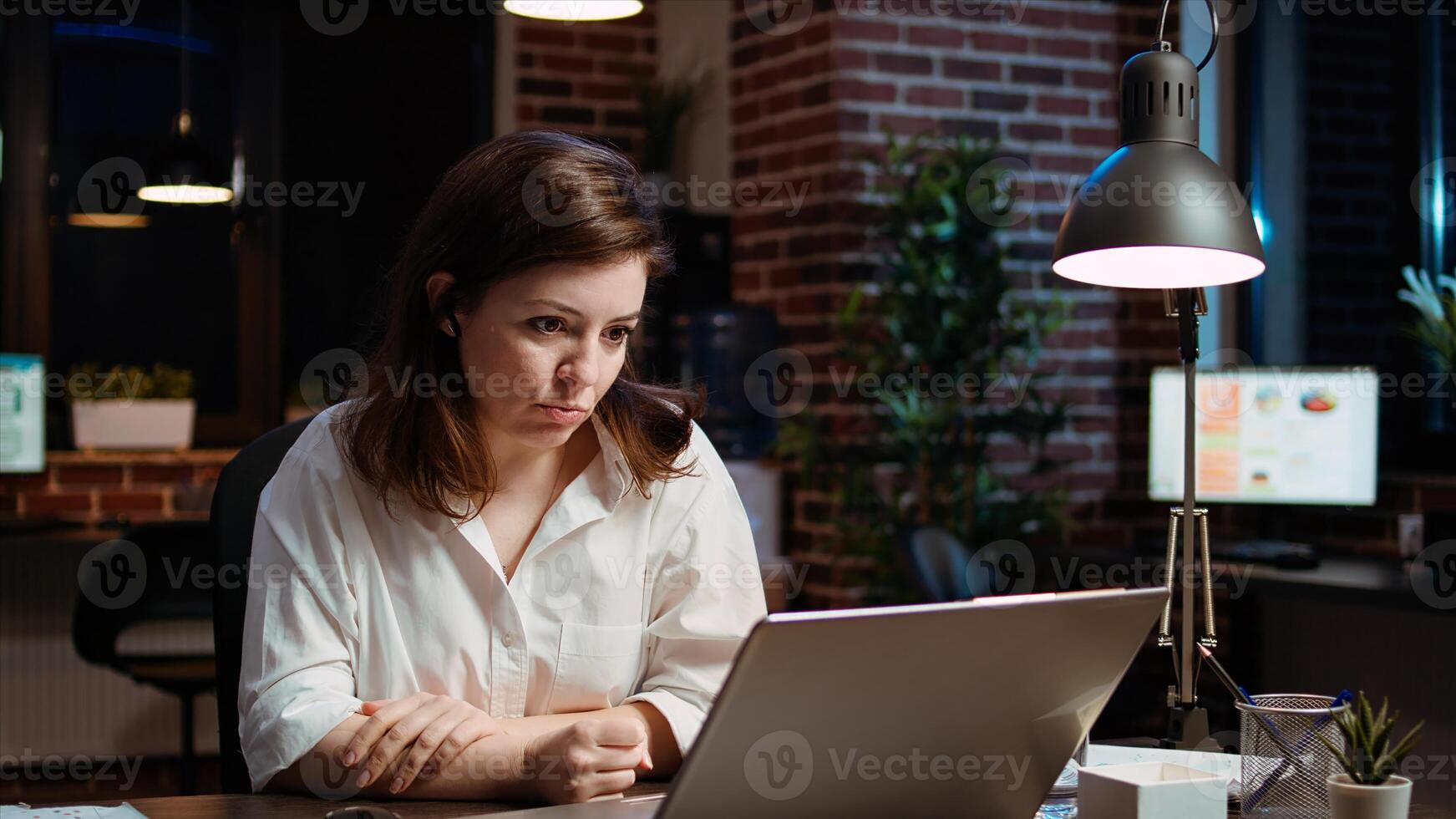 Employee calls manager remotely using internet videocall to ask for feedback on project progress. Worker in brick wall office requesting assistance from team leader in teleconference meeting, camera A photo