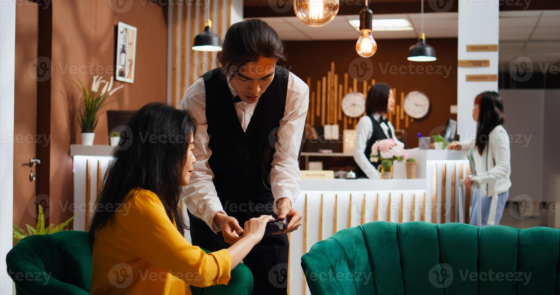 Hotel guest paying for drink and giving cash to worker, feeling happy with customer services and offering money tip. Tourist using credit card to pay at pos terminal, relaxing in lounge area. photo