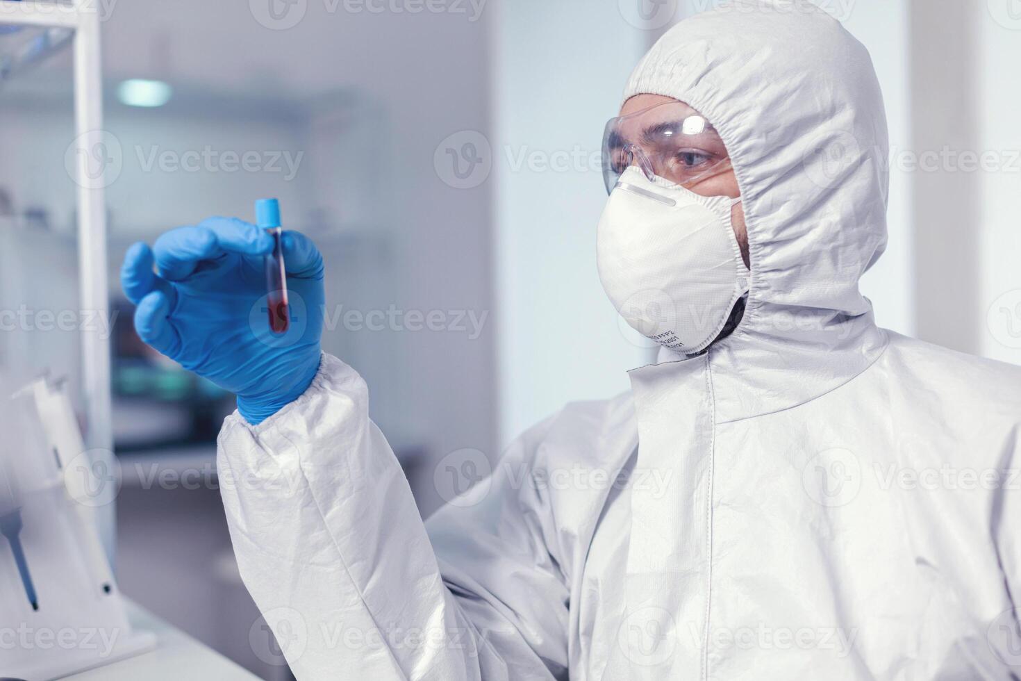 Chemist during coronavirus outbreak working with blood sample dressed in ppe. Doctor working with various bacteria and tissue, pharmaceutical research for antibiotics against covid19. photo