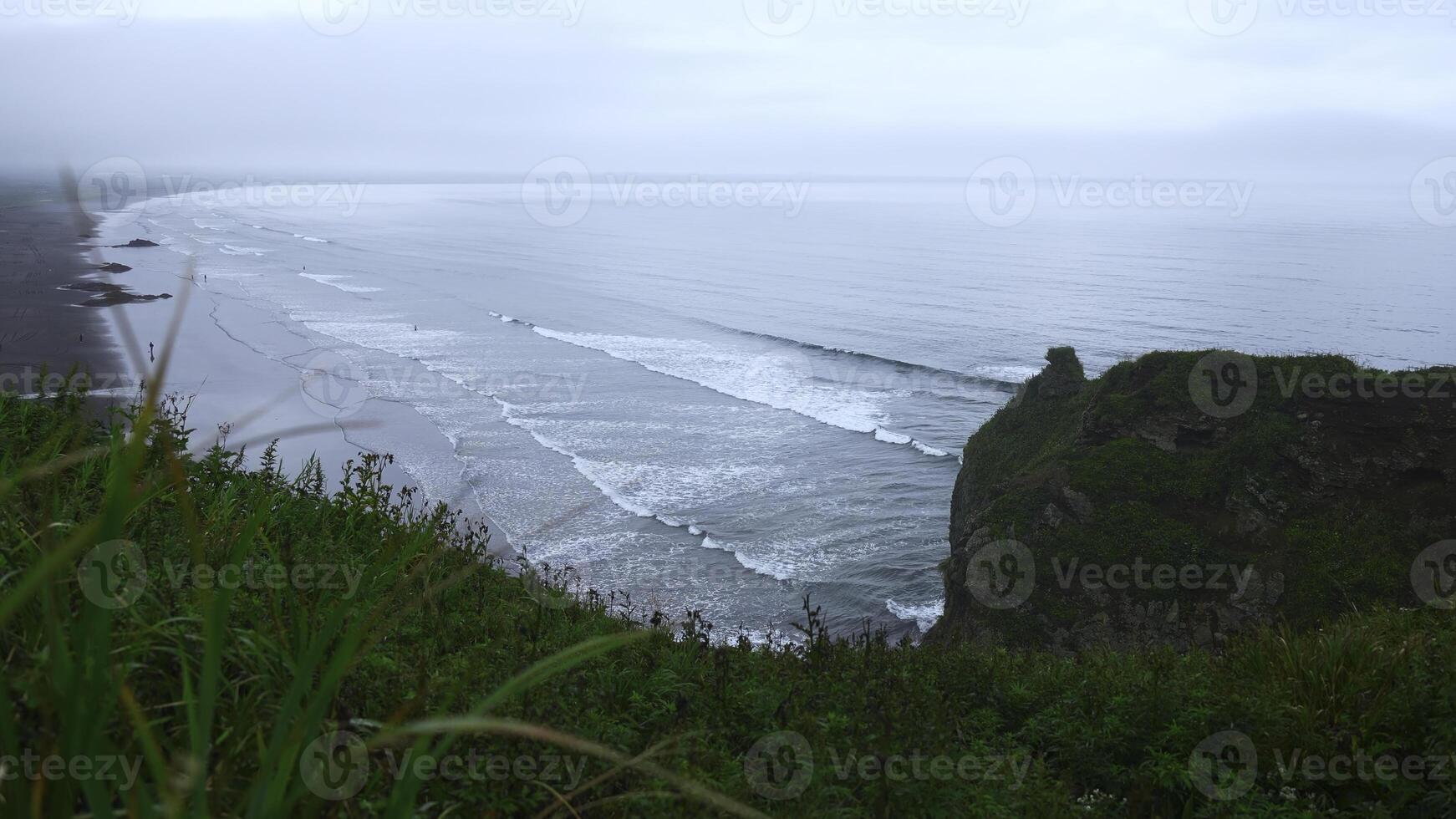 View with beautiful green grass on cliff of sea coast. Clip. Landscape of rocky coast with green grass and sea horizon on cloudy day. View from mountain coast to beautiful waves on summer day photo