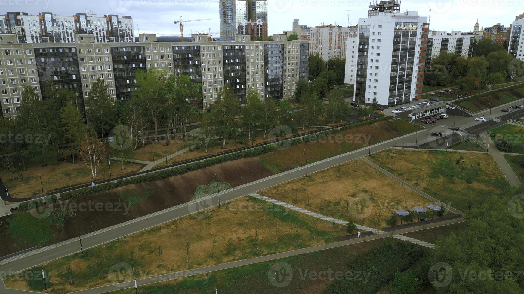 Top view of park alley in residential area of city. Clip. View of city with residential buildings and park alley. Beautiful landscape of park alley in urban landscape with buildings photo