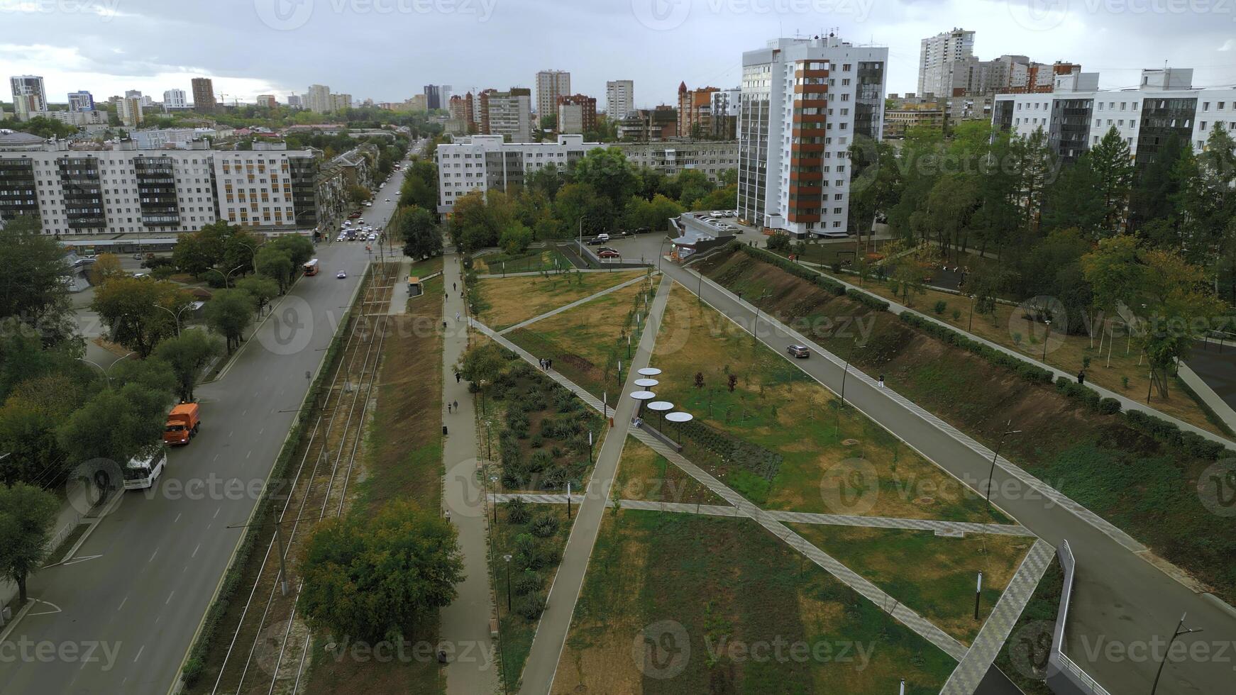 Top view of park alley in residential area of city. Clip. View of city with residential buildings and park alley. Beautiful landscape of park alley in urban landscape with buildings photo