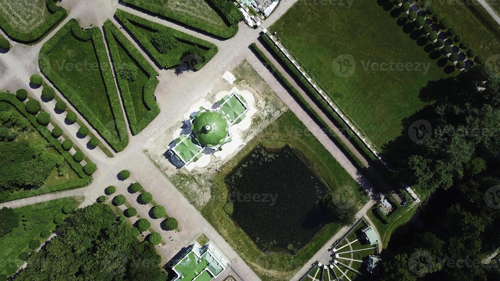 Top view of old estate with garden and pond. Creative. Beautiful garden area with patterns of paths and pond on sunny summer day. People walk in royal garden on estate photo