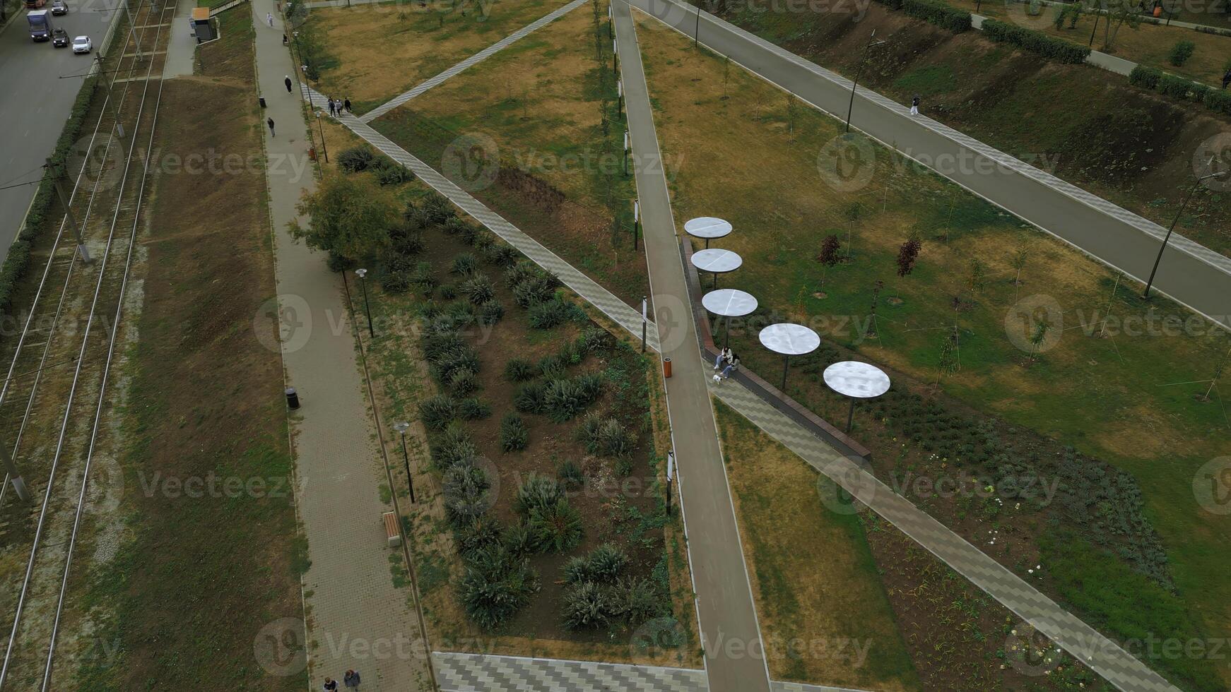 Top view of people walking in park alley in city. Clip. People walk and relax in modern city park. Landscape of city park alley with solar panels photo