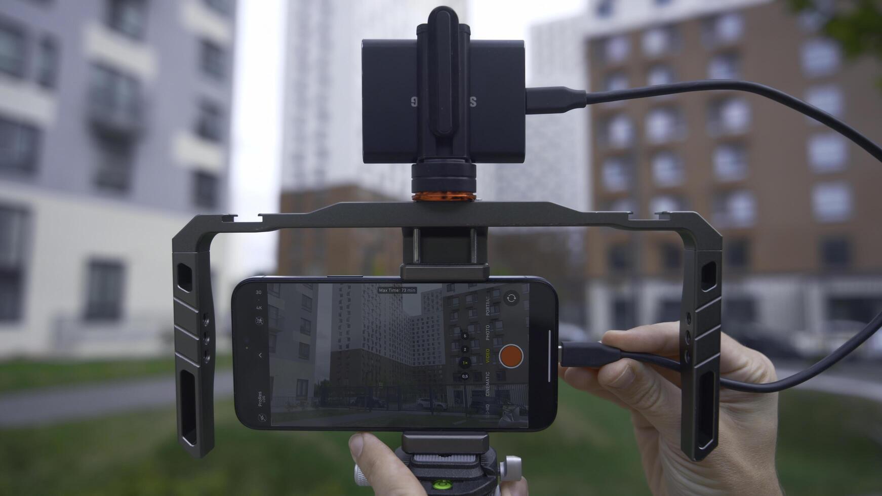 China, Beijing - September 15, 2023. Connecting professional stabilizer to phone for shooting. Action. New iPhone 15 pro with additional gadgets for professional shooting. Stabilizer and screen with photo