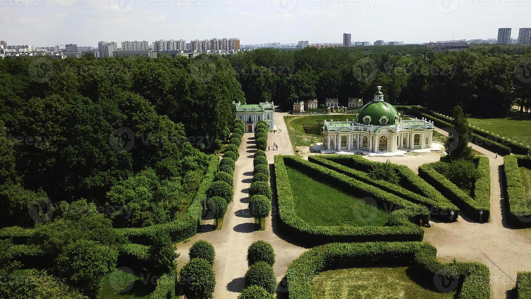 Top view of people walking on territory of palace garden. Creative. Beautiful road of palace garden with beautiful bushes and trees. Old building of royal estate with garden on sunny summer day photo