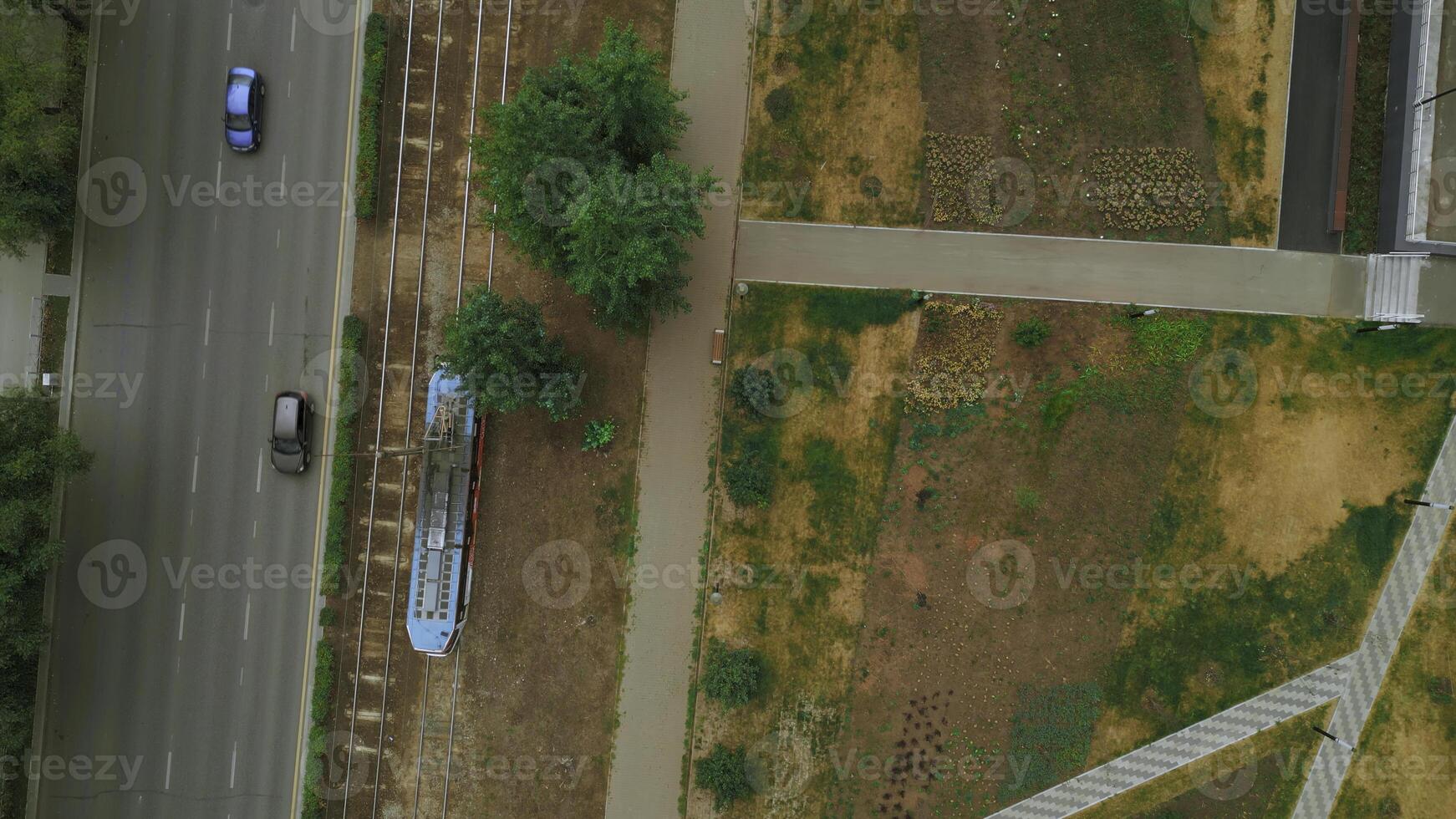 Top view of modern tram in city with park. Clip. Tram in motion on rails in city in summer. Tram rides at park alley in city photo