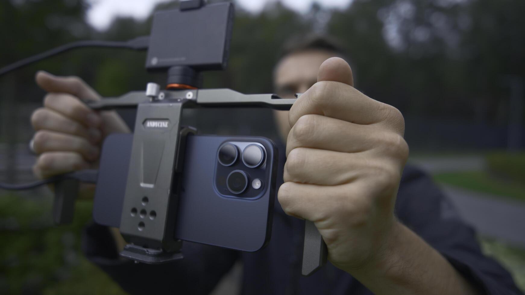 UK, London - September 15, 2023. Man professionally shoots on phone with stabilizer. Action. Cinematic shooting on new iPhone 15 pro. Shooting with stabilizer for cinematic effect with new iPhone 15 photo