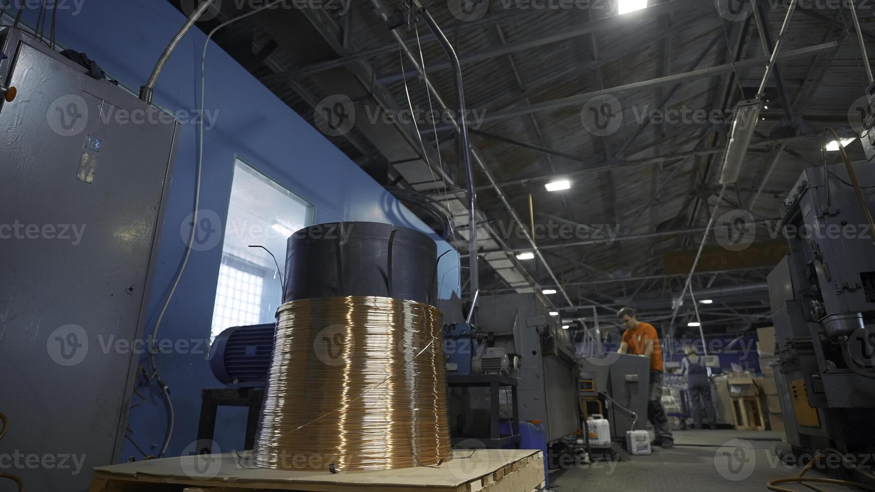 Copper wire on industrial coil with working. Creative. Worker adjusts operation of industrial machines on control panel. Industrial settings of machines with copper wires photo