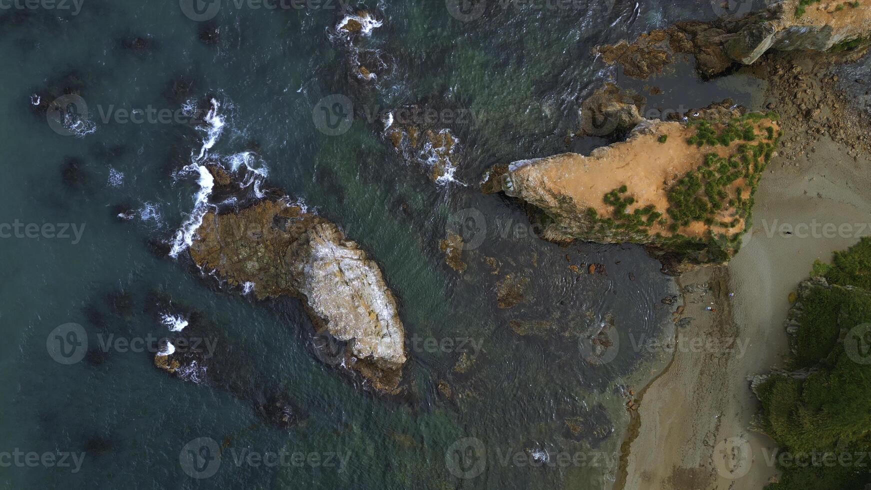 Top view of beautiful wild coast with rocks in water. Clip. Coastline with rocks and waves near shore. Inspiring nature of sea coast with variety of rocks photo