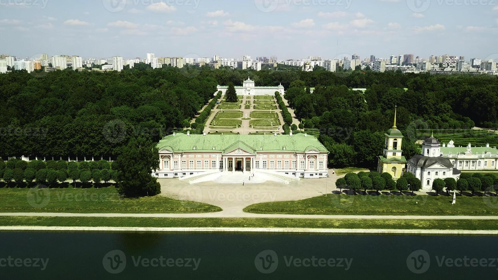 Palace with pond on background of modern city. Creative. Top view of beautiful historical complex on sunny summer day. Palatial buildings with garden and pond with contrast of modern city on horizon photo