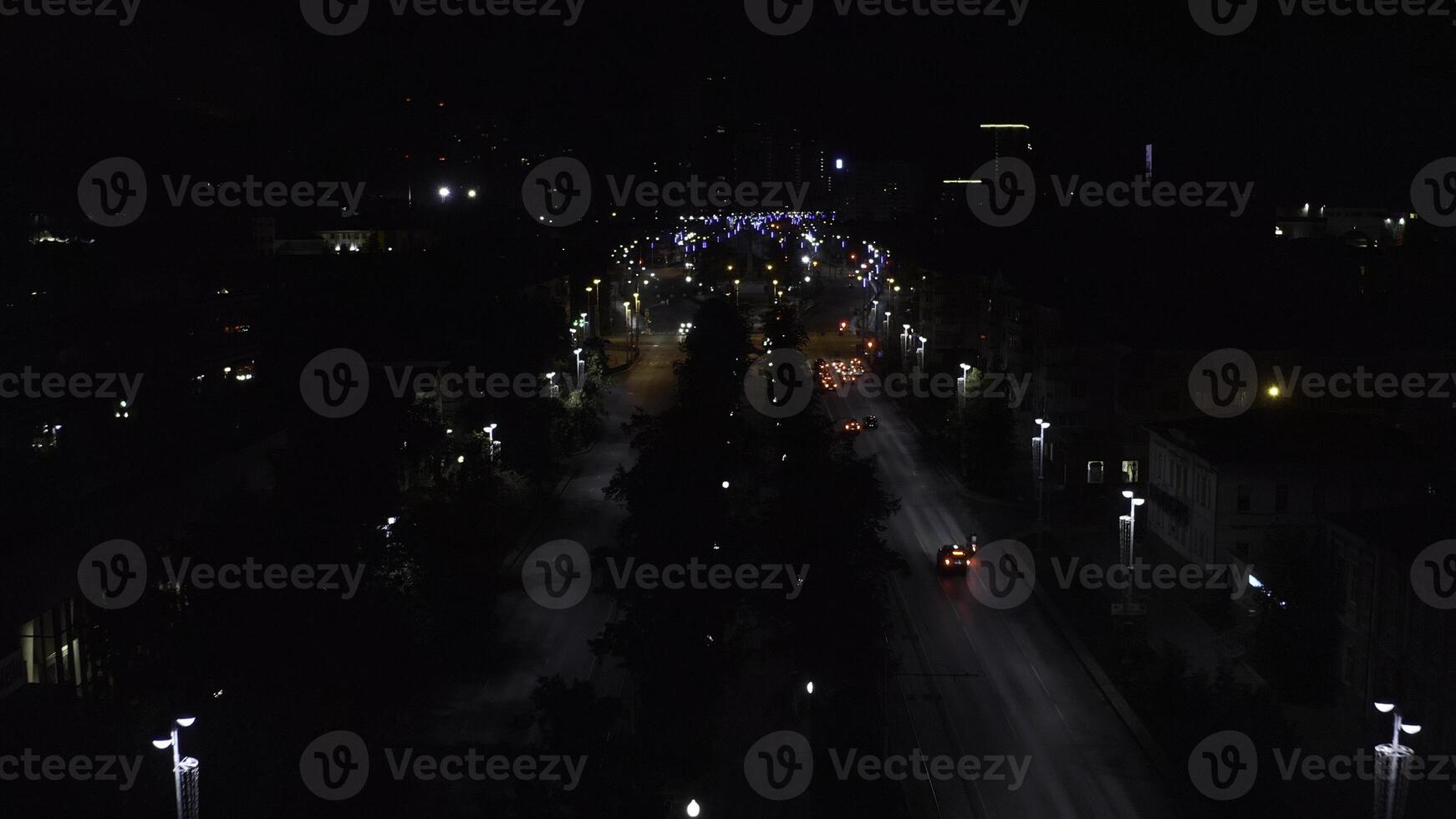 Top view of dark city at night with glowing lanterns. Stock footage. Beautiful view of highway with cars and lanterns. Night road in the center of modern city with lanterns photo