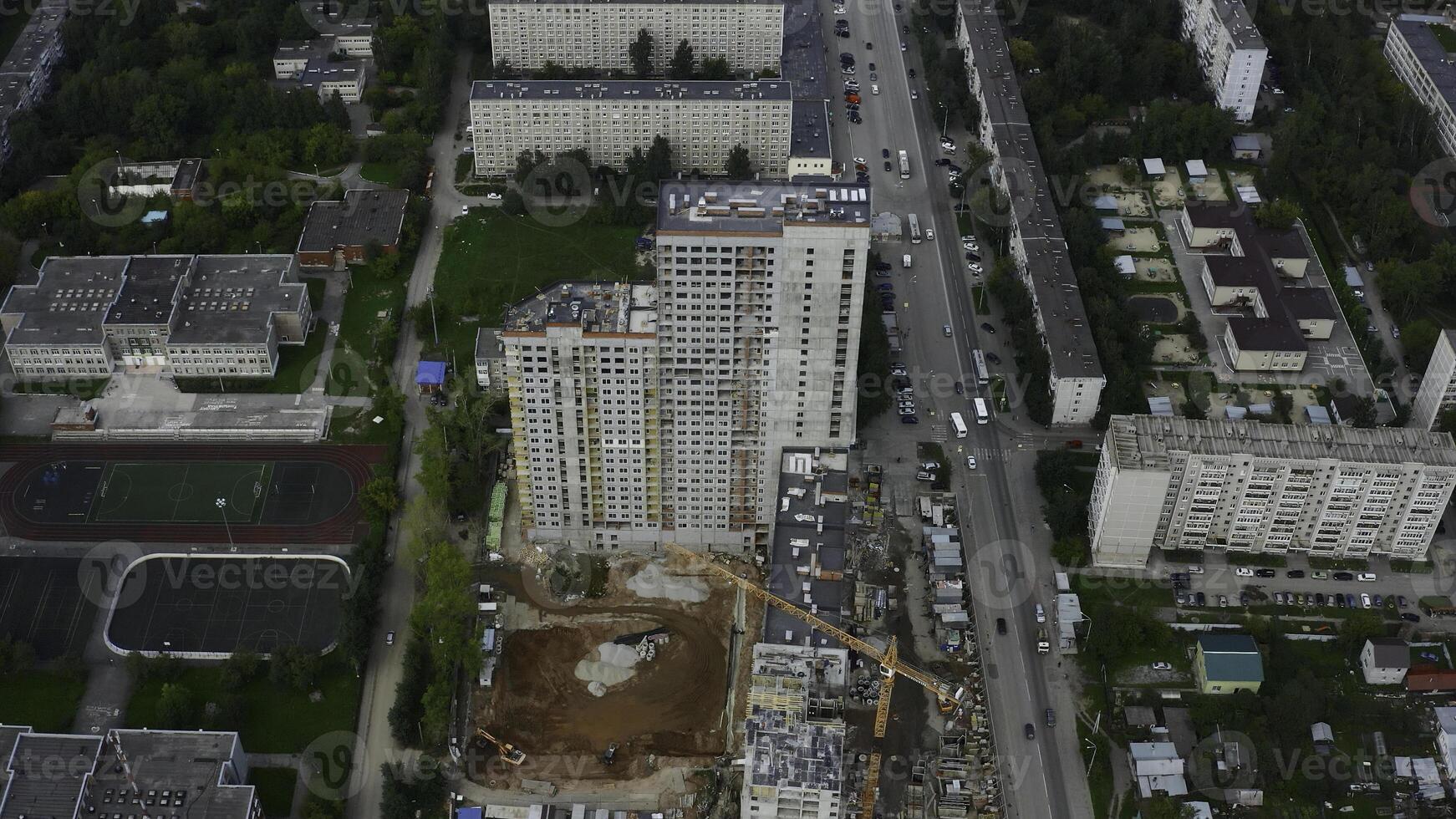 Top view of construction of multi-storey building in city. Stock footage. Construction of multi-storey building in city center on summer day. Panorama of modern city with construction of high-rise photo