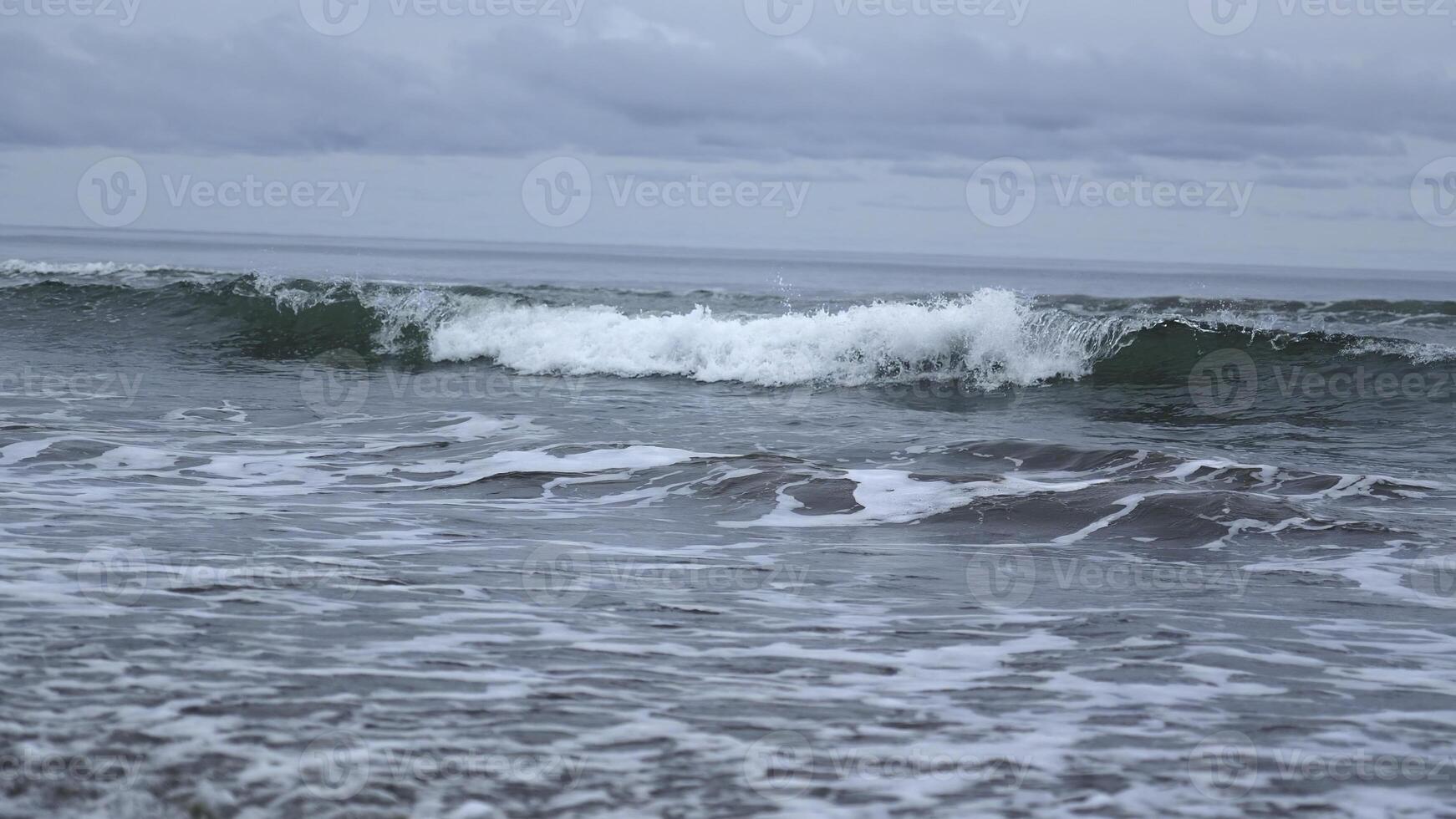 Seascape of beautiful waves on cloudy day. Clip. Beautiful coastal waves on background of horizon with cloudy sky. Coastal waves of North Sea on cloudy day photo