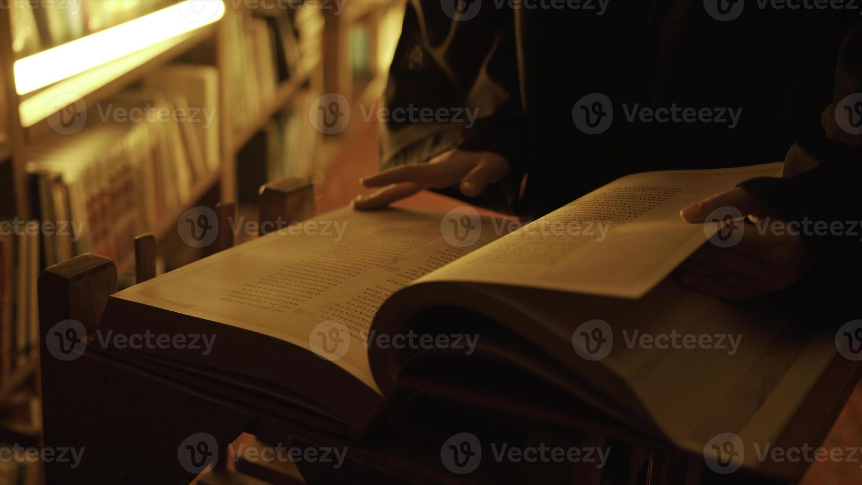 Man reading large mysterious book. Stock footage. Close-up of mysterious man reading ancient forbidden book in library. Secret society with books in night library photo