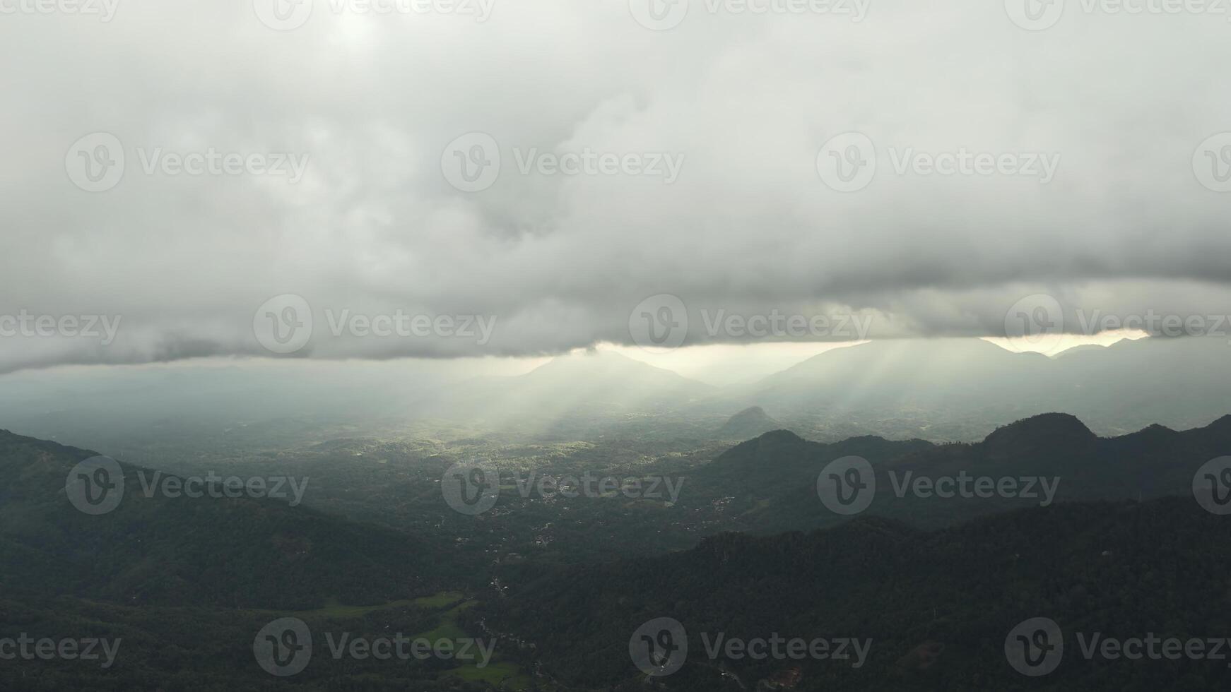 Beautiful view of mountain green valley with clouds and sunlight. Action. Picturesque landscape of green mountains and low clouds with sun breaking through. Sun's rays on horizon in green mountain photo