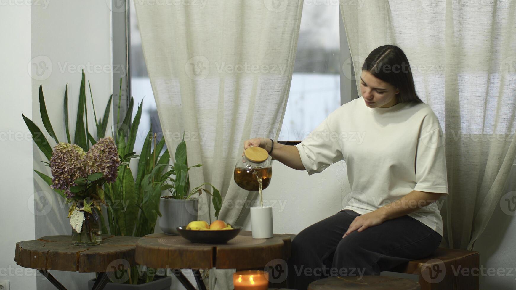 joven mujer con entusiasmo bebidas té en cafetería. medios de comunicación. joven mujer bebidas calentamiento té en acogedor café por ventana en invierno. calentamiento té en acogedor café en invierno día foto