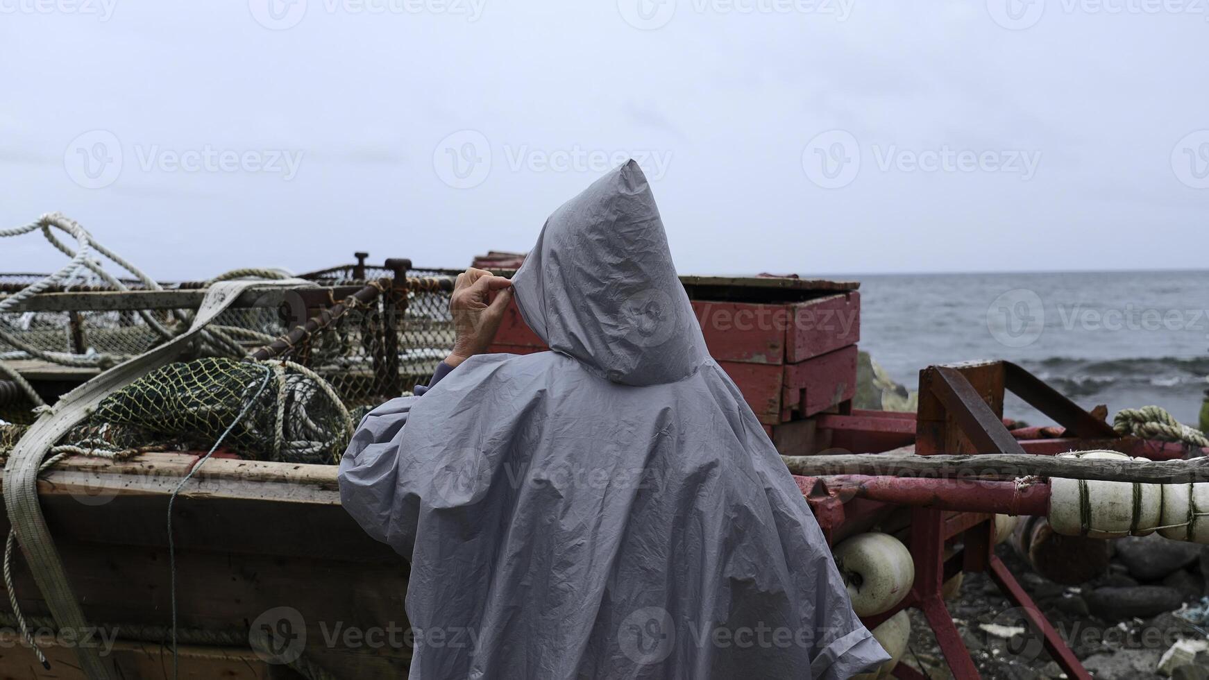 Man walks along pier to fishing boat. Clip. Man on stone pier goes to fishing boat. Man walks along embankment with fishing boats on cloudy day photo