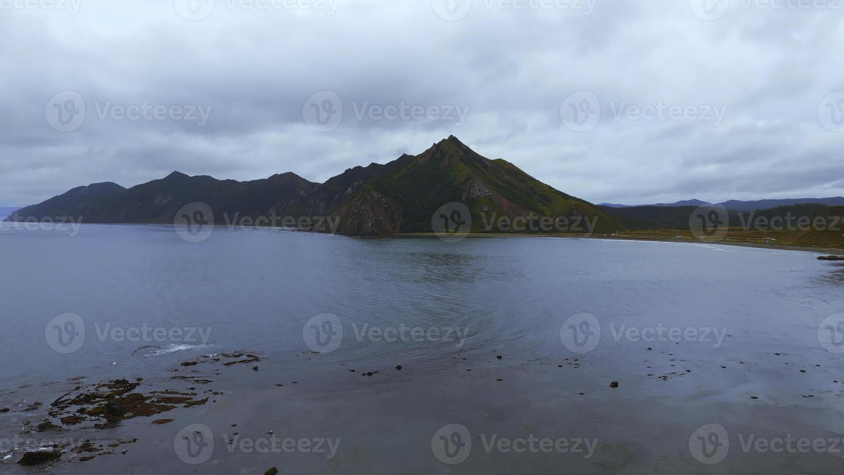 Northern reef coast of sea with mountains. Clip. Top view of reef seascape with mountain views on cloudy day. Cinematic view of coast with mountains on horizon photo