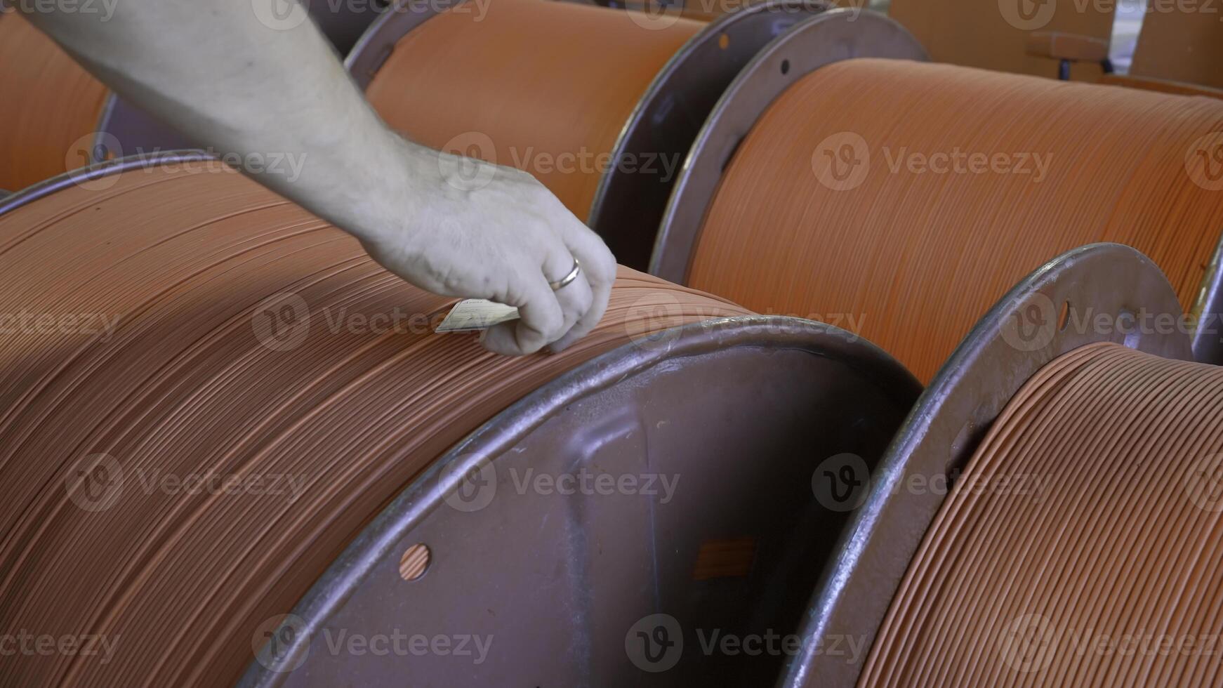 Close-up of worker with wires on coils in factory. Creative. Worker numbers coils with wires at factory. Ready-made coils with rubber wires in industrial enterprise photo