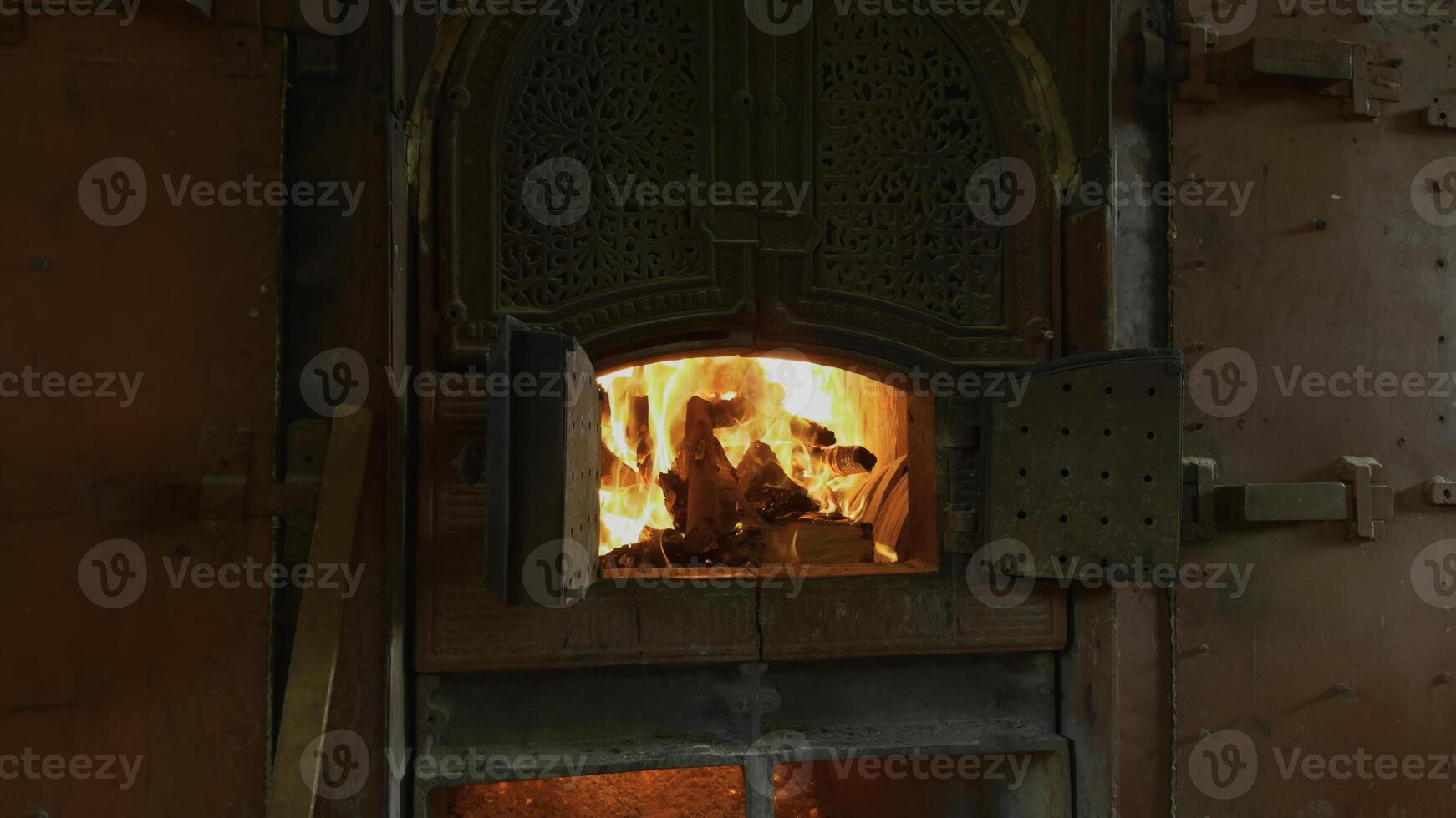 Old stove with firewood in summer. Action. Beautiful oven doors in wall with fire. Outdoor stove with burning wood inside on summer day photo
