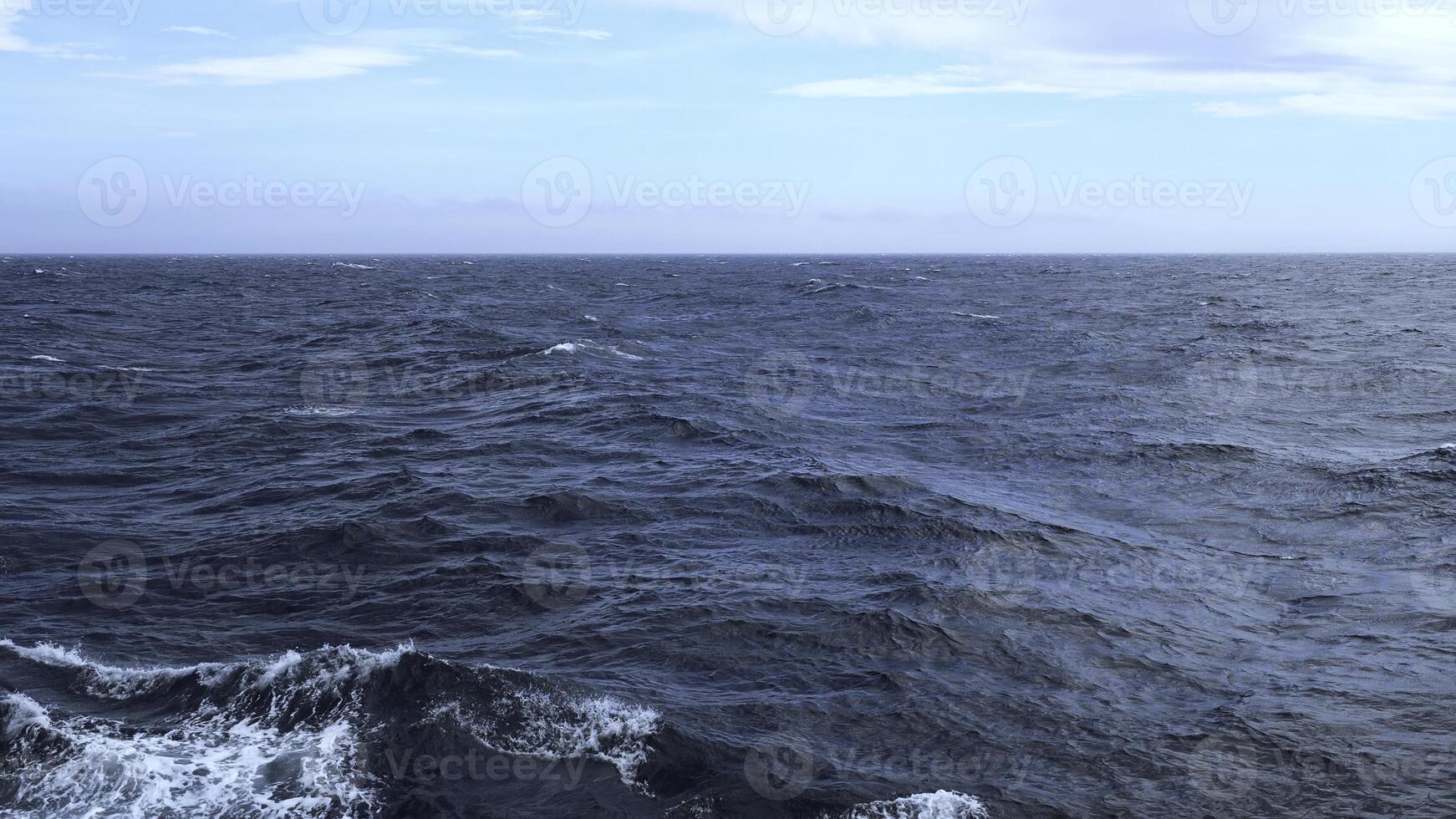 Beautiful view of horizon of blue sea with waves. Clip. Foam from waves in blue sea. In blue sea with waves on background horizon with blue sky photo