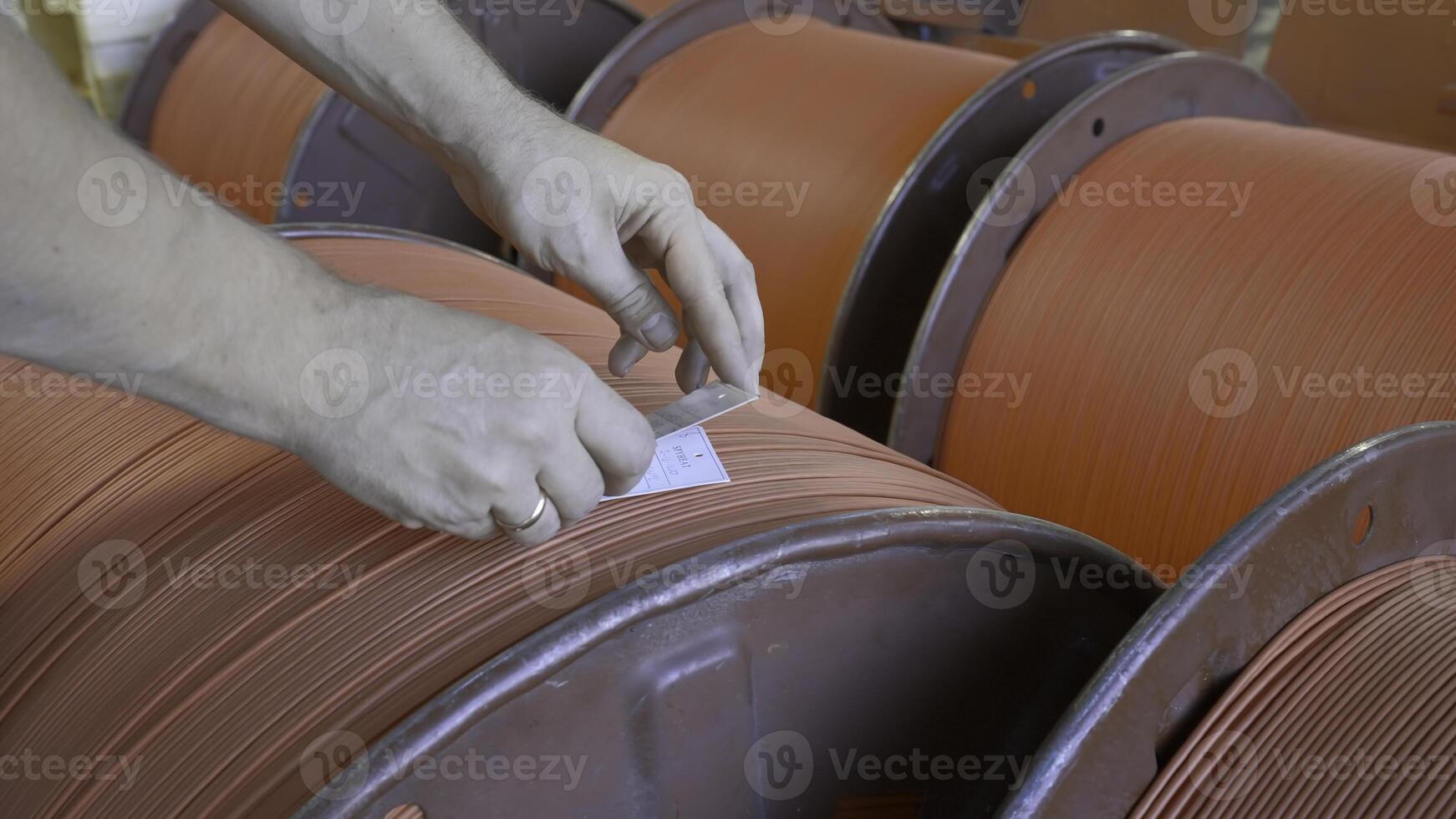 Close-up of worker with wires on coils in factory. Creative. Worker numbers coils with wires at factory. Ready-made coils with rubber wires in industrial enterprise photo