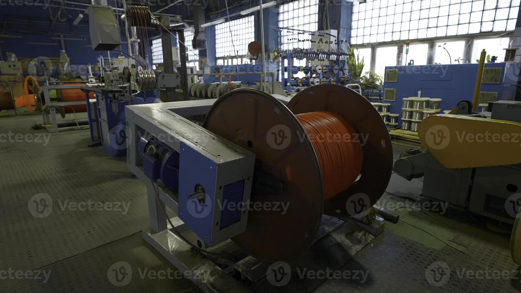 Rotating coil with wires in factory. Creative. Winding cable on to coil on production machine. Process of winding cables at metallurgical plant photo