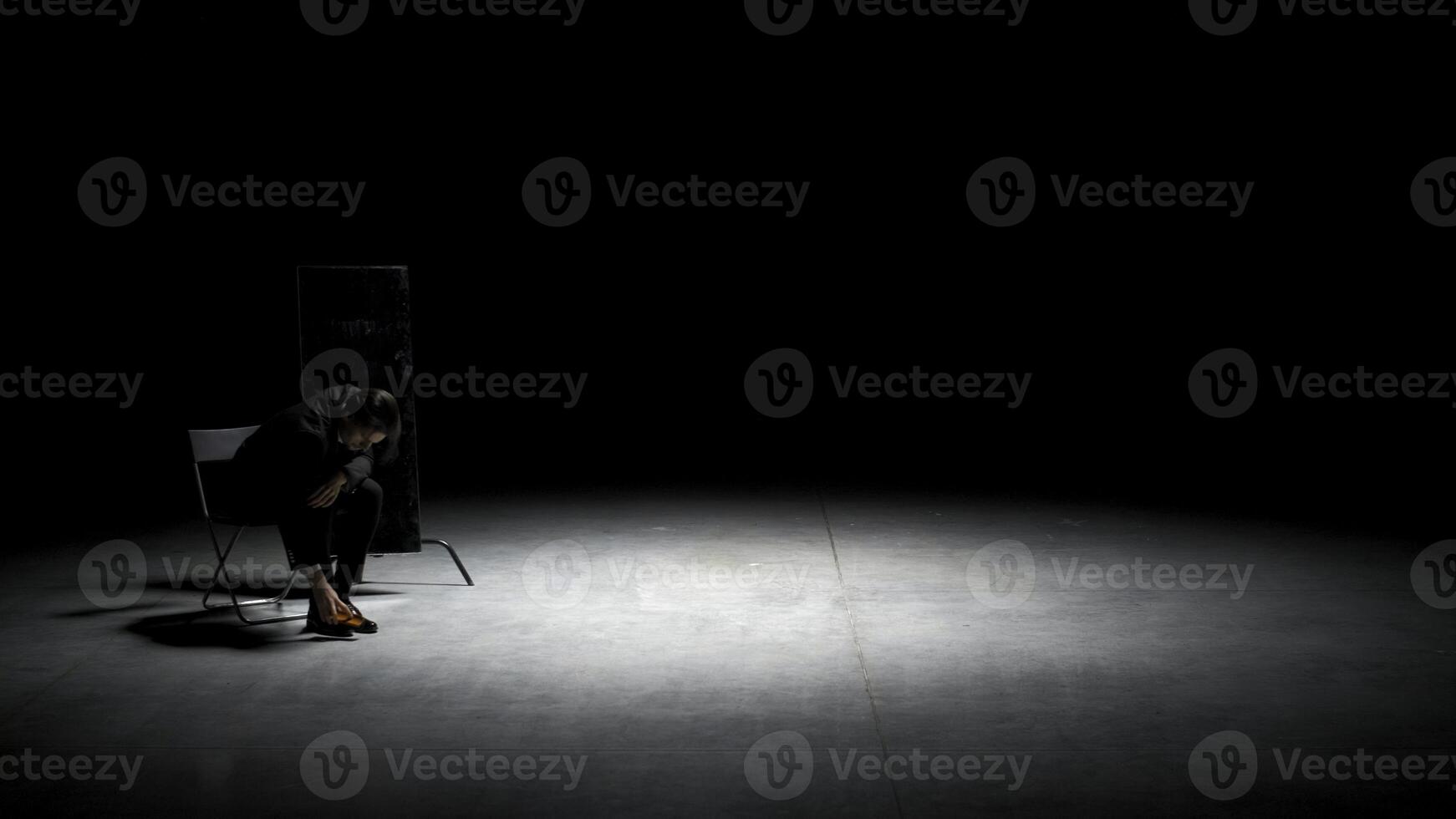 hombre en traje limpia su zapatos. valores imágenes. teatral producción con uno actor en negocio traje limpieza zapatos. hombre en traje se sienta en silla y limpia Zapatos en etapa foto