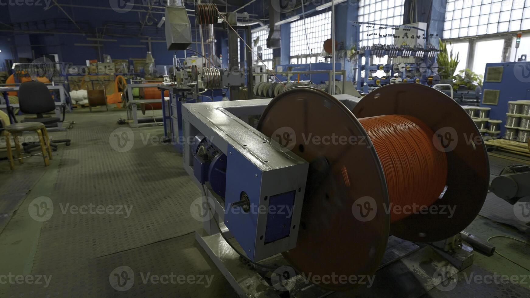 Rotating coil with wires in factory. Creative. Winding cable on to coil on production machine. Process of winding cables at metallurgical plant photo