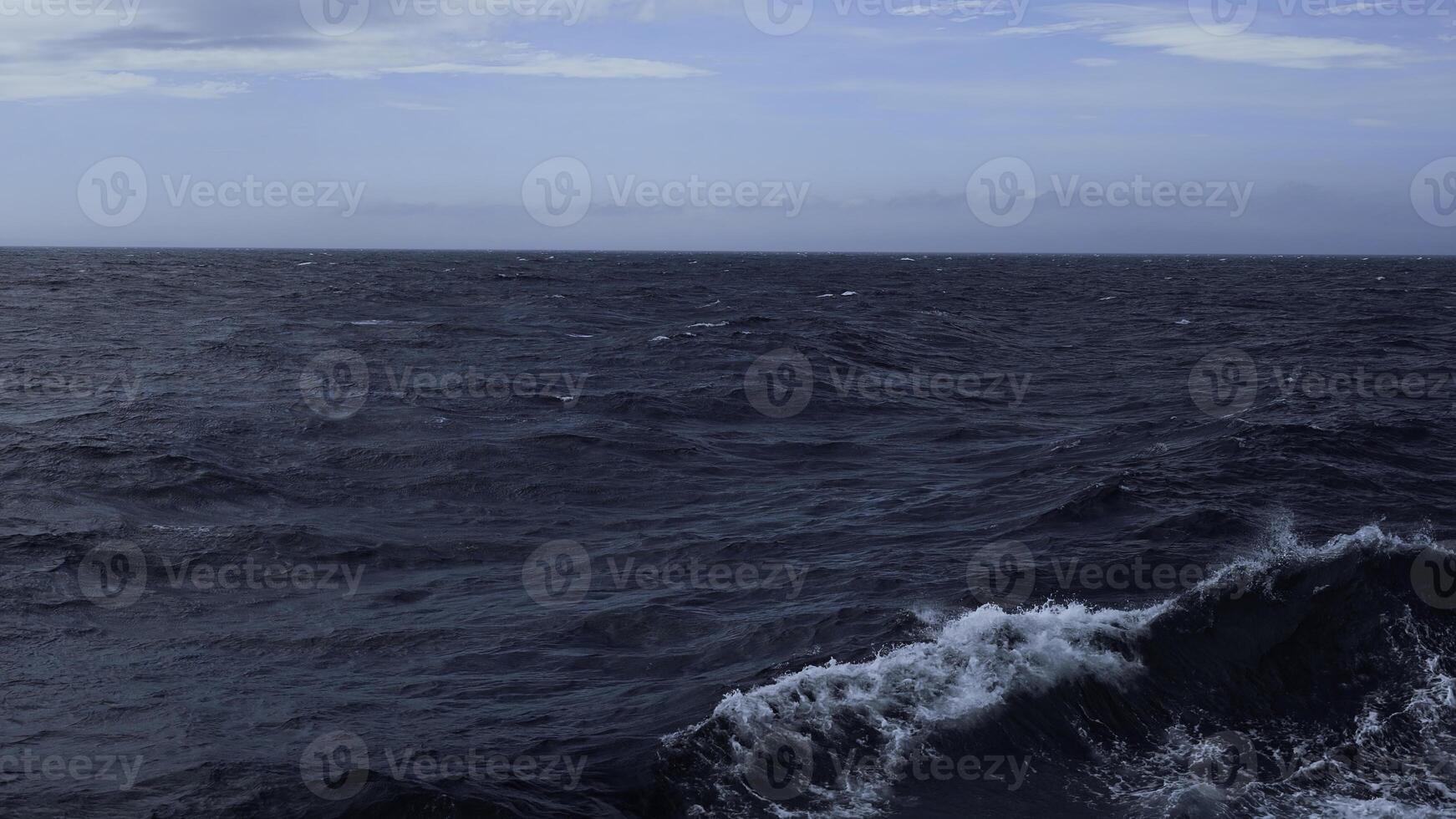 Beautiful view of horizon of blue sea with waves. Clip. Foam from waves in blue sea. In blue sea with waves on background horizon with blue sky photo