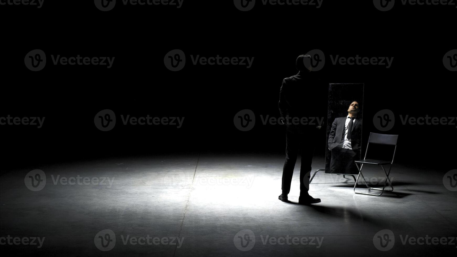 Man in suit alone on theater stage. Stock footage. Single attractive man in suit is playing on stage of theater. Man in suit with mirror is alone on dark theatrical stage photo