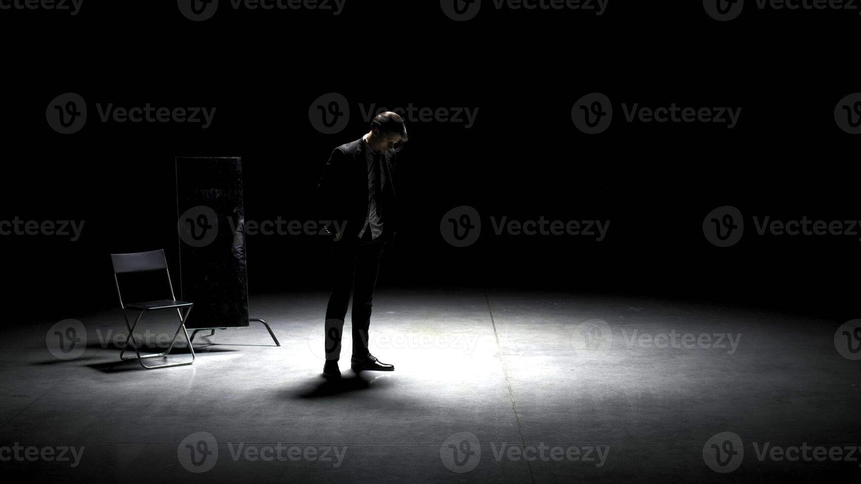 hombre en traje solo en teatro escenario. valores imágenes. soltero atractivo hombre en traje es jugando en etapa de teatro. hombre en traje con espejo es solo en oscuro teatral etapa foto