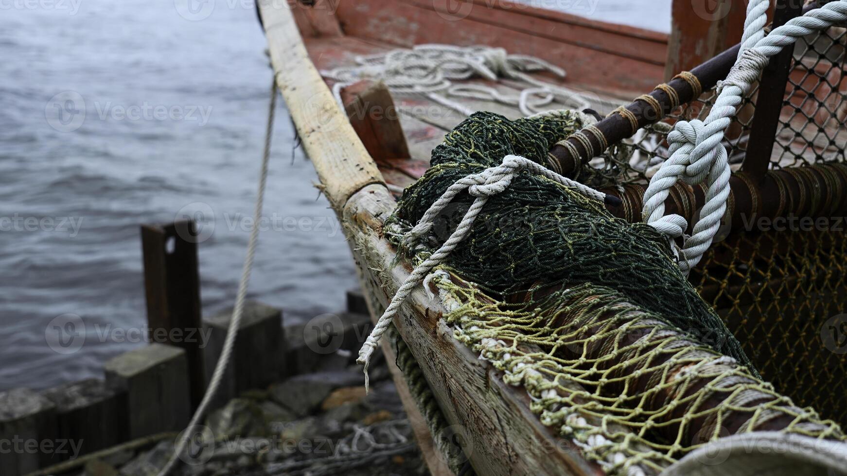 Close-up of fishing boat on wooden pier. Clip. Fishing nets on wooden boat standing on sea pier. Beautiful details of sea fishing boat on cloudy day photo