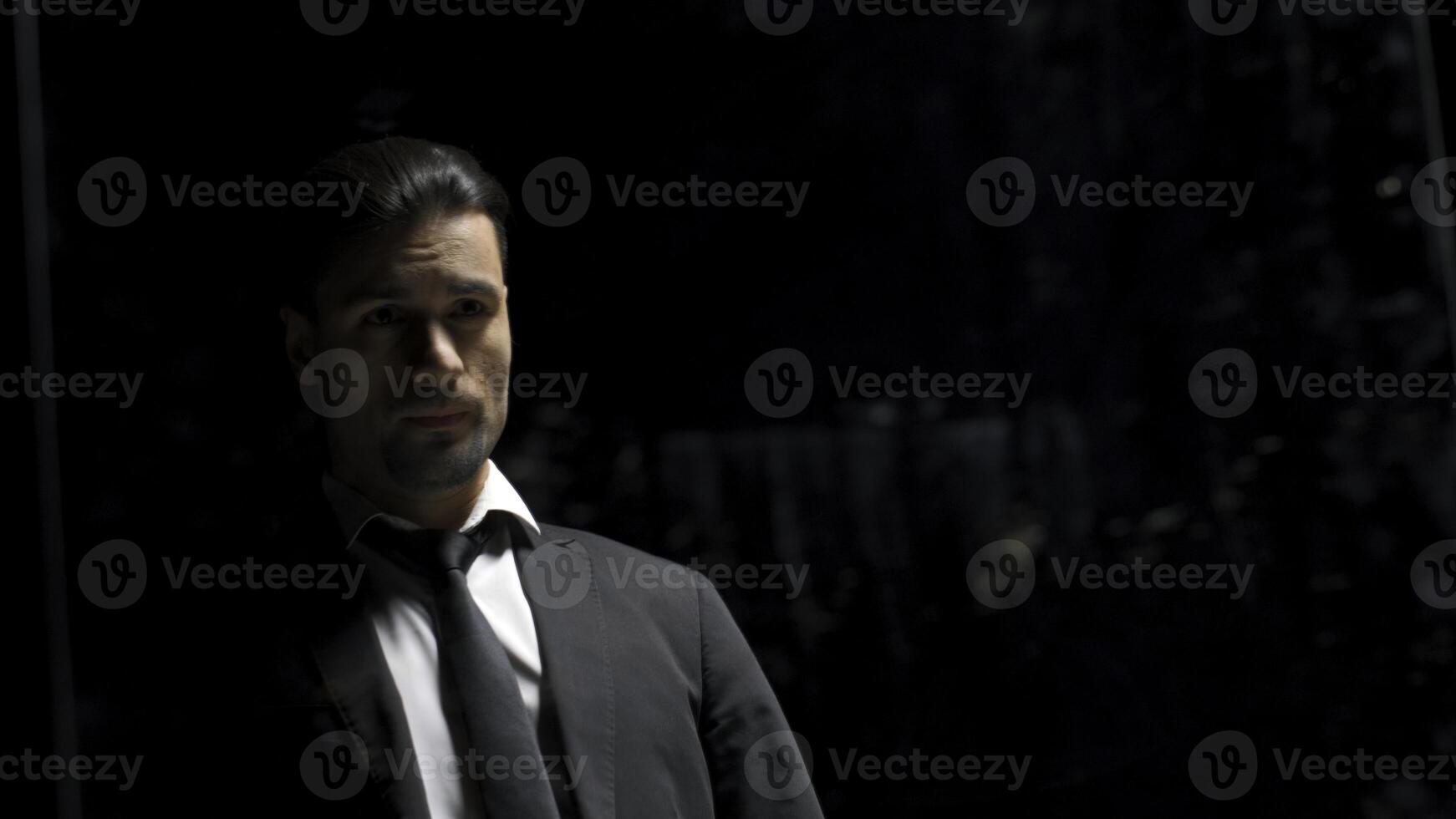 Reflection in mirror of man in suit on black background. Stock footage. Man in suit is preparing for something in front of mirror. Theatrical production with reflection of man in suit in mirror photo