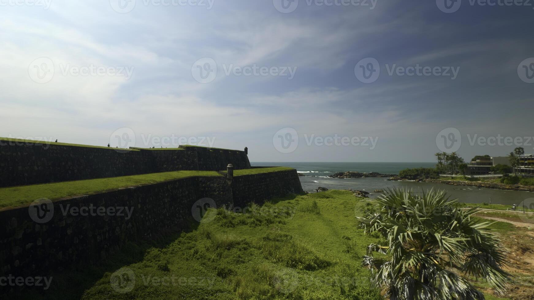Beautiful old fortress with greenery and sea view. Action. Beautiful landscape with ancient fortress overgrown with green grass on seashore. Fortress with grass by sea on sunny summer day photo